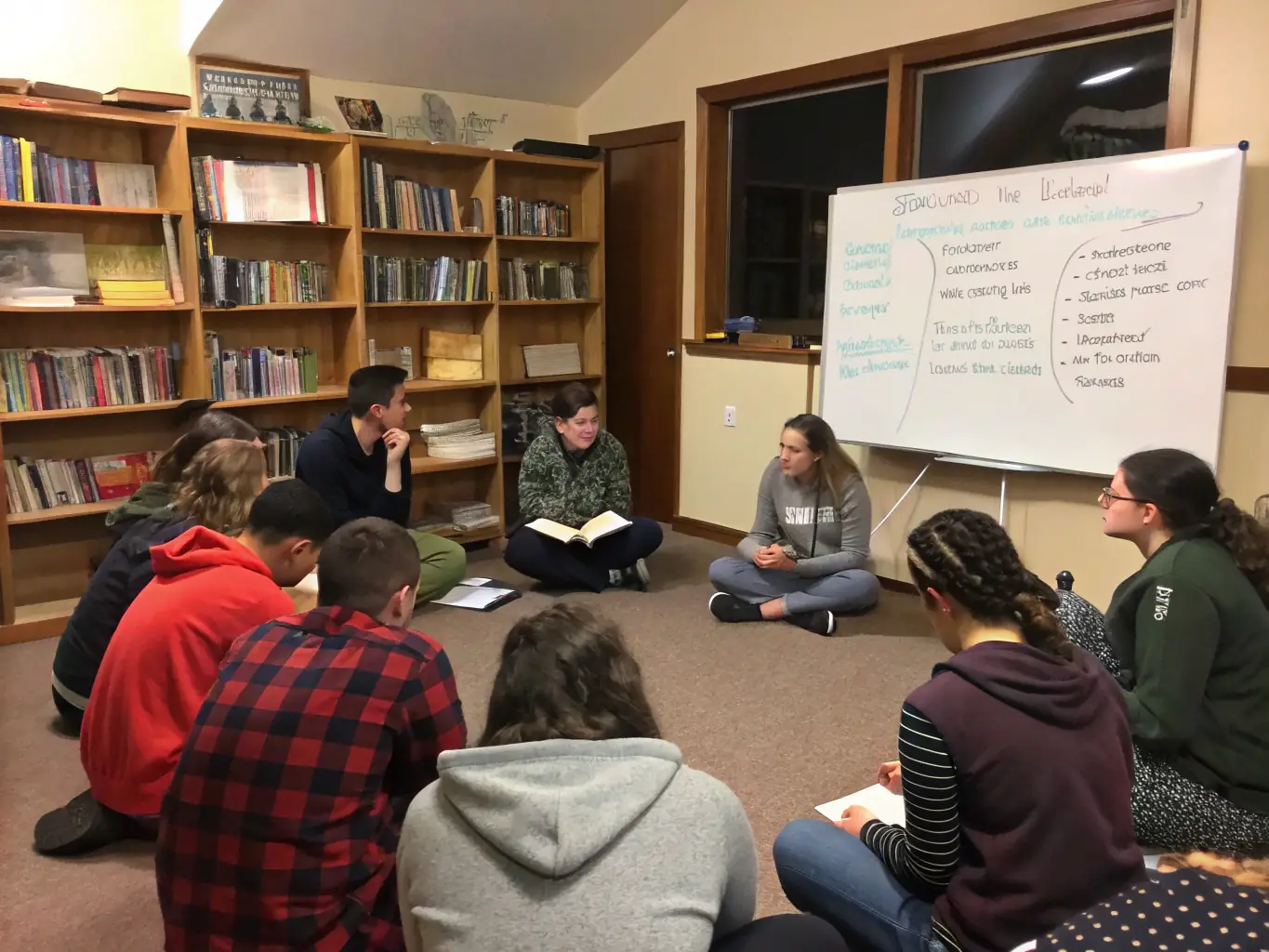 A group of students engaged in a lively classroom discussion with a pastor leading the session, representing the Ministerial Theology Diploma program.